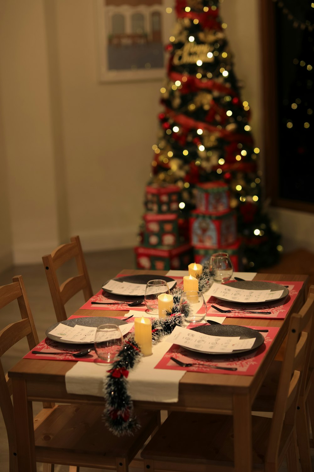 a table set for a christmas dinner with a christmas tree in the background