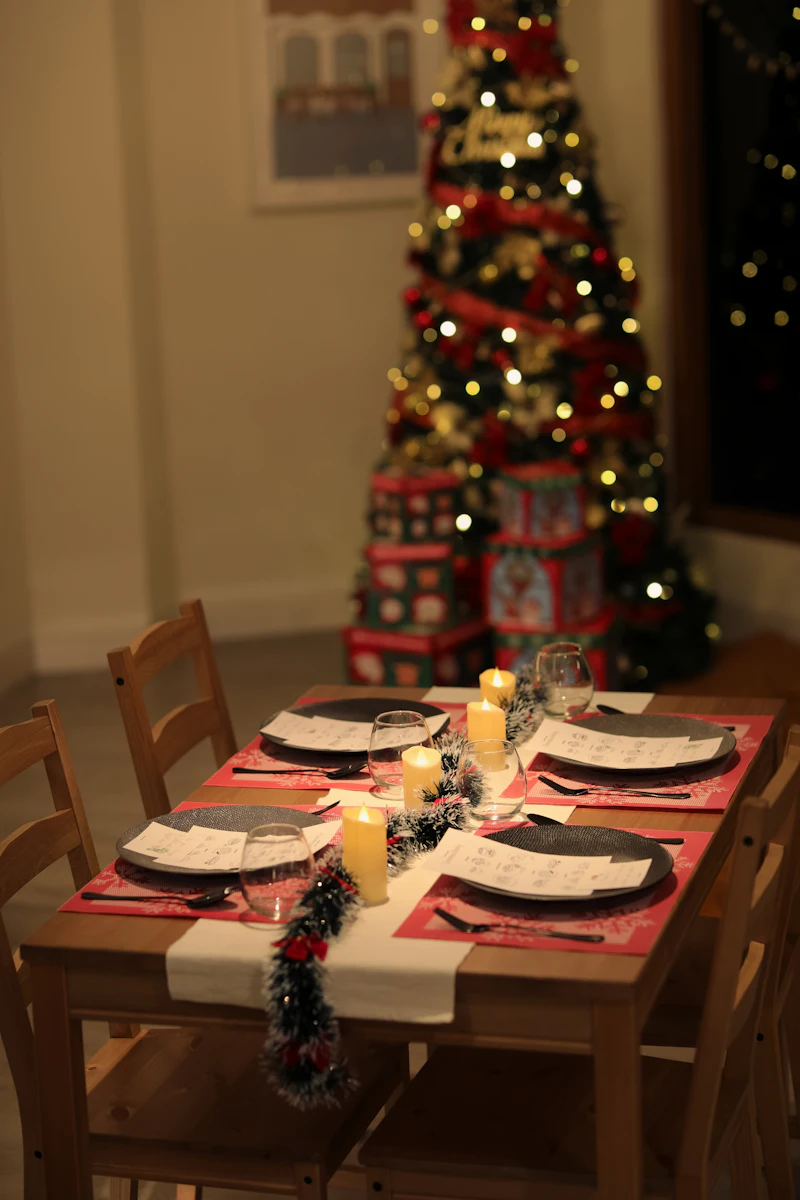 A table set for Christmas dinner with the tree behind it