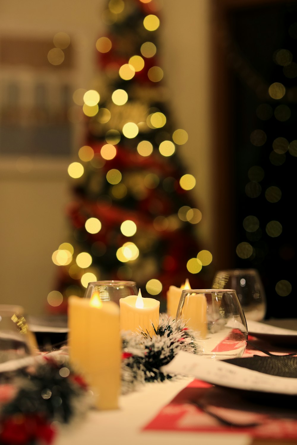 a lit candle on a table with a christmas tree in the background