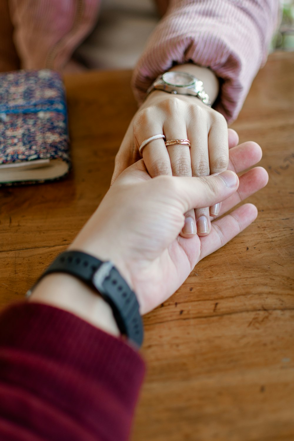 a person holding the hand of another person on a table