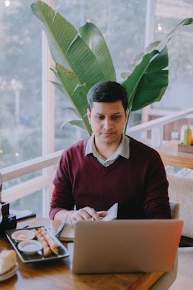 A cheerful traveler practicing Spanish on a tablet while sitting at a sunny café abroad.
