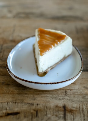 A slice of classic cheesecake with a golden crust on a rustic plate