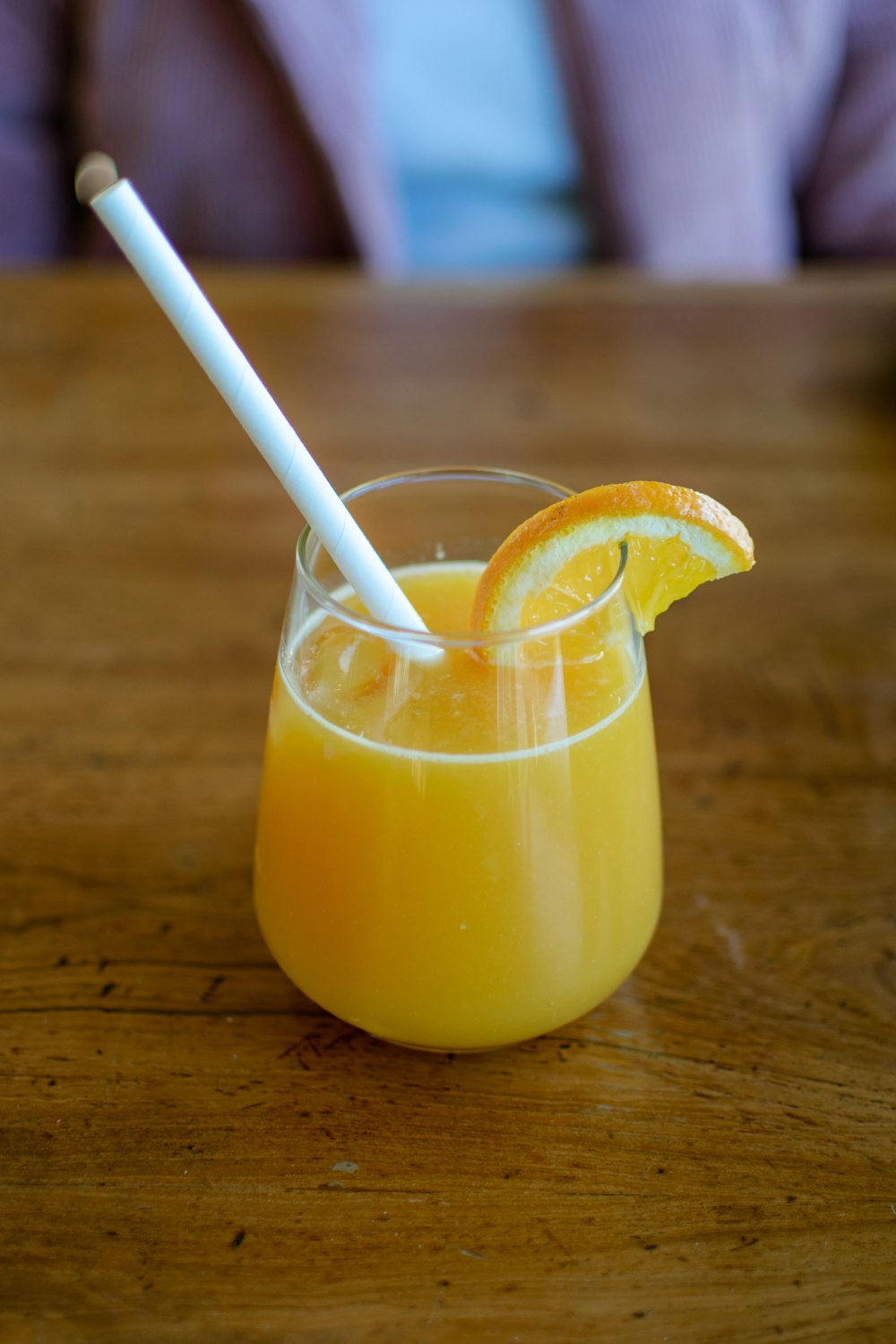 a glass of orange juice with a straw in it