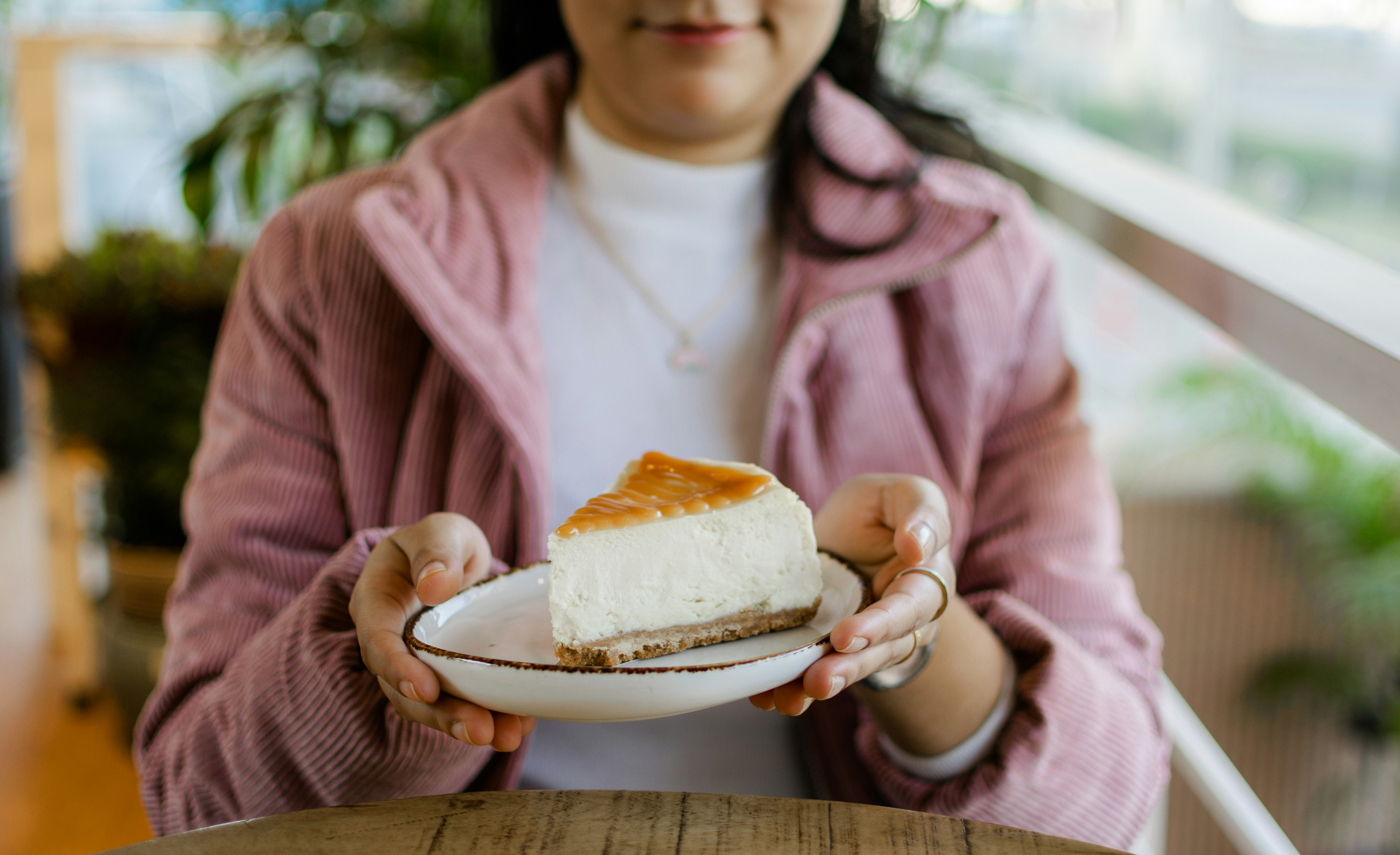 A woman holding a plate with a piece of cake on it