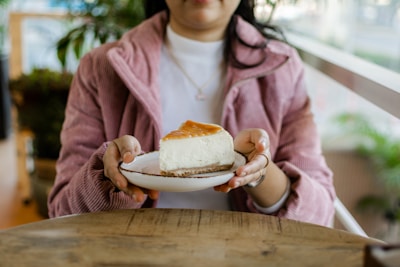 A cheerful person enjoying a slice of Albina Cheesecake in a cozy kitchen setting.
