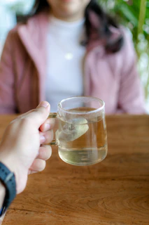 a person holding a cup of tea on a table