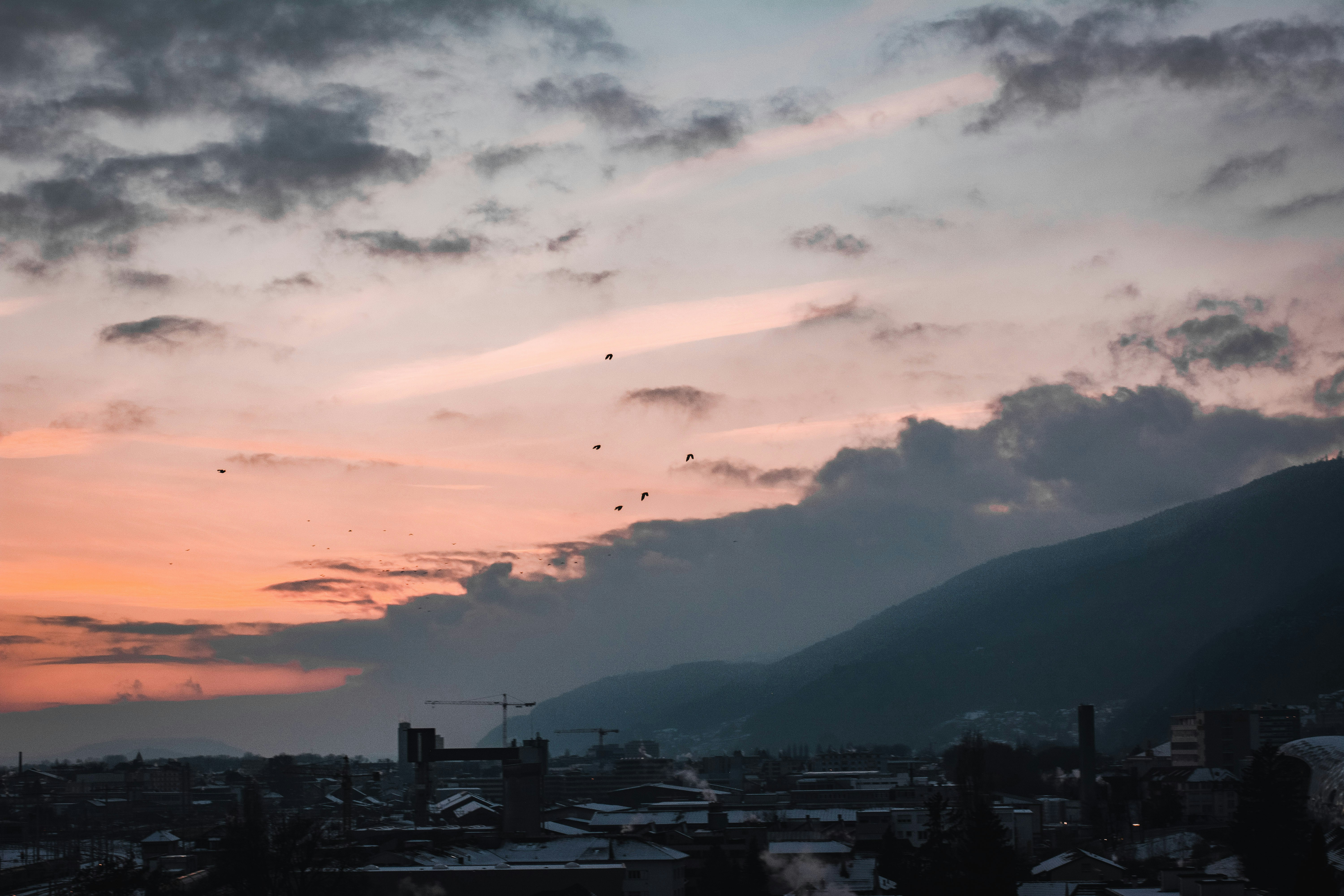 a sunset view of a city with mountains in the background
