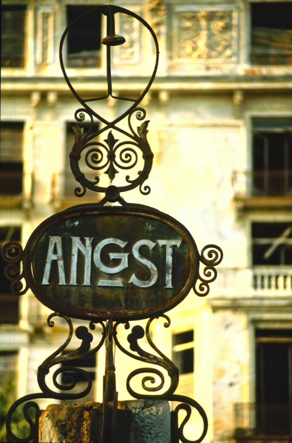 a rusted sign hanging from the side of a building