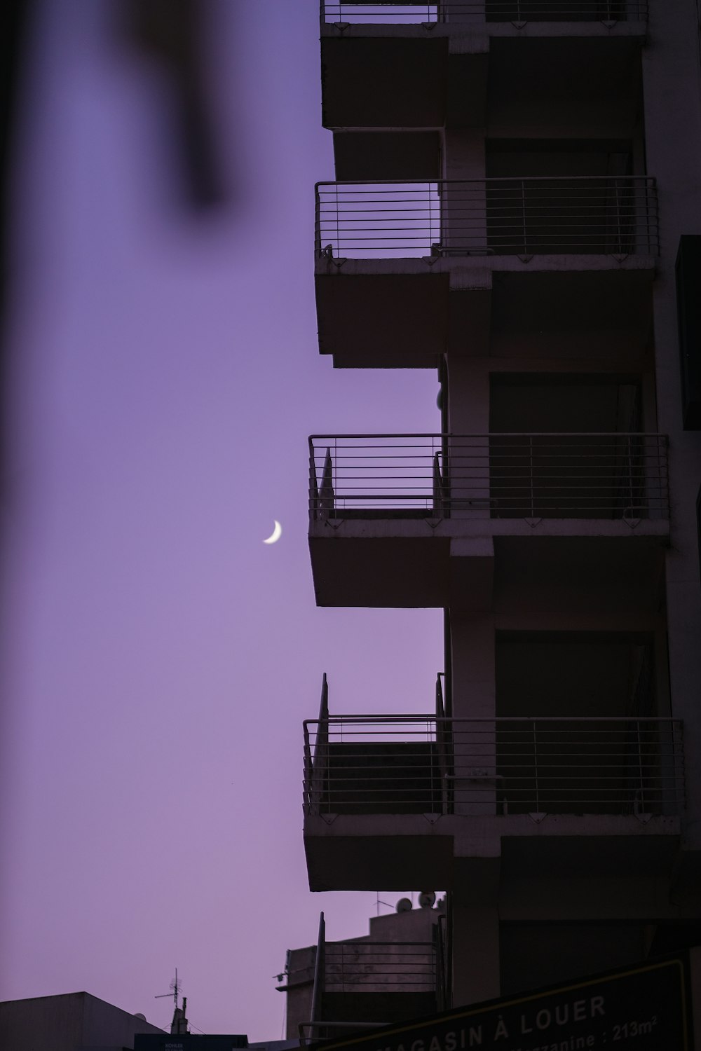 a building with balconies and a half moon in the sky