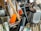 A collection of kitchen utensils and tools is densely packed, including a grater, knife sharpener, wooden spoon, and silicone brush. The utensils are made of metal, plastic, and wood, with some items overlapping each other.