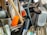 A collection of kitchen utensils and tools is densely packed, including a grater, knife sharpener, wooden spoon, and silicone brush. The utensils are made of metal, plastic, and wood, with some items overlapping each other.