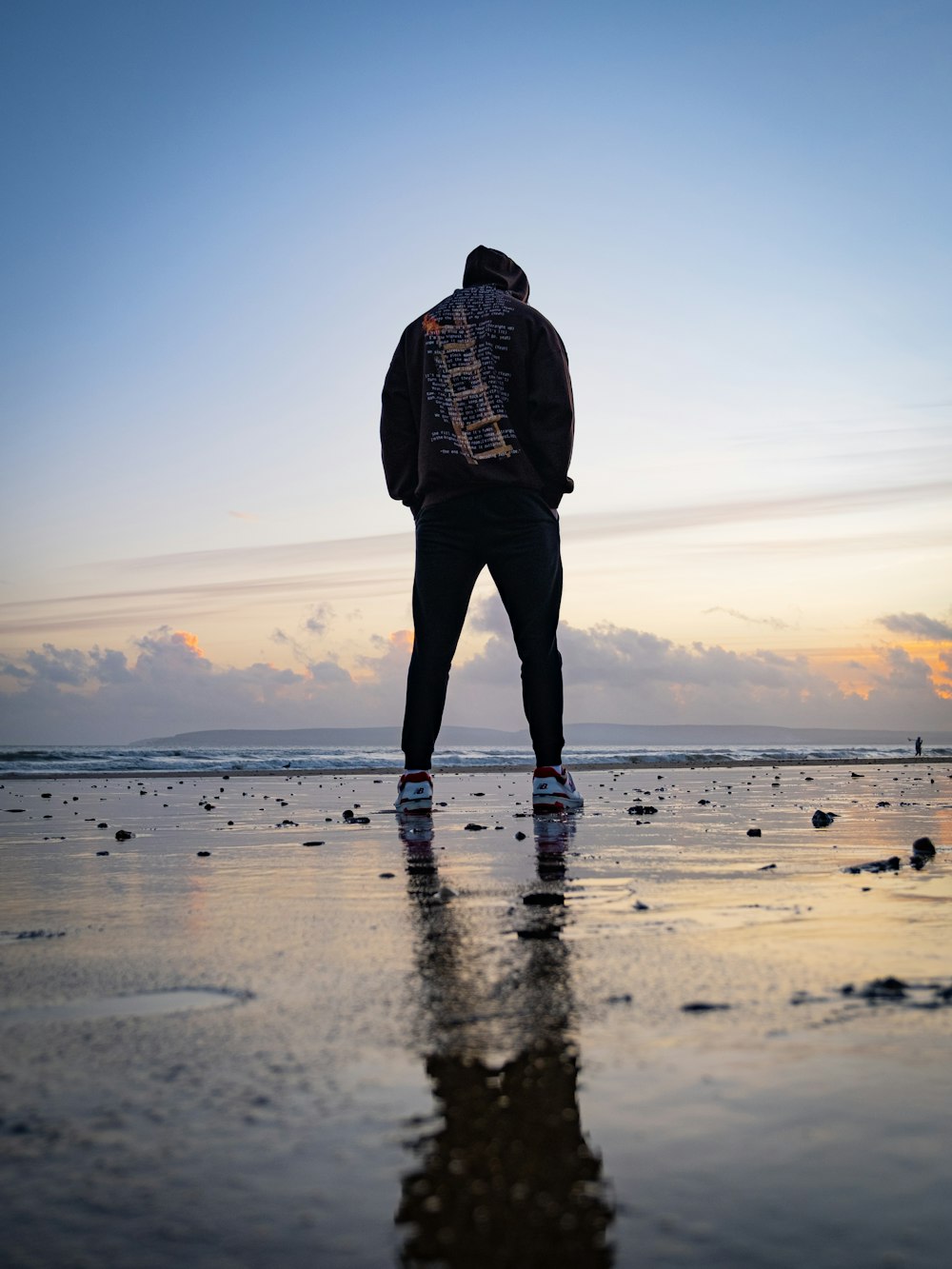 a man standing on a beach at sunset