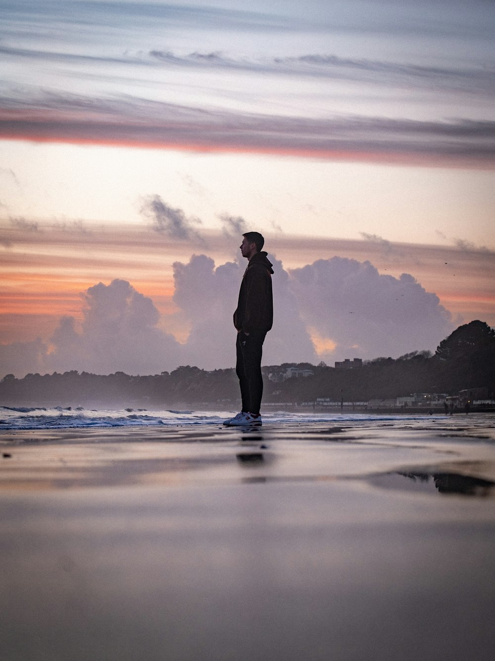 a man standing on top of a beach next to the ocean