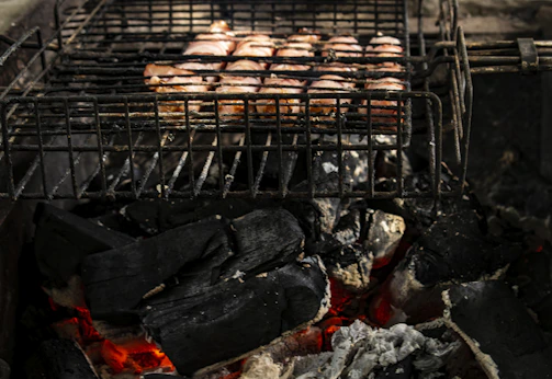 A vibrant shot of a charcoal grill glowing warmly with flames licking the edges of juicy meat.