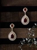 a pair of red and white earrings sitting on top of a wooden table