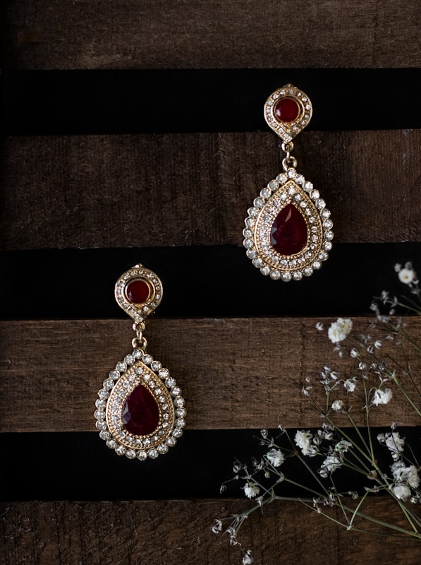 a pair of red and white earrings sitting on top of a wooden table