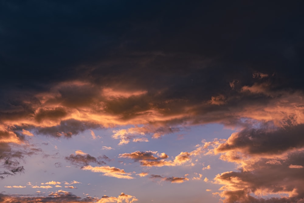 a plane flying through a cloudy sky at sunset