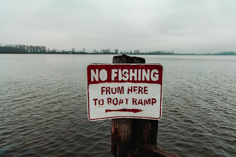 a no fishing sign on a wooden post in the water