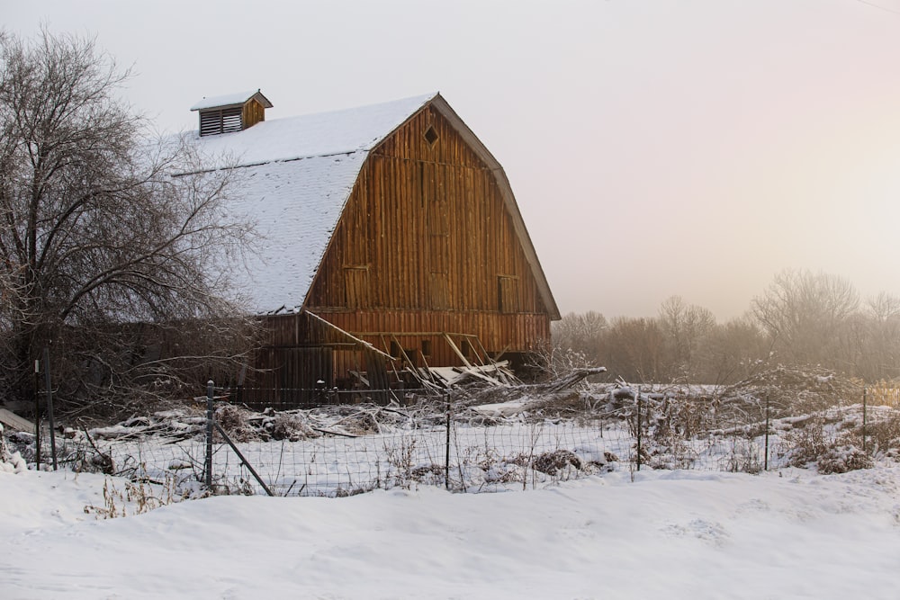 a barn in the middle of a snowy field