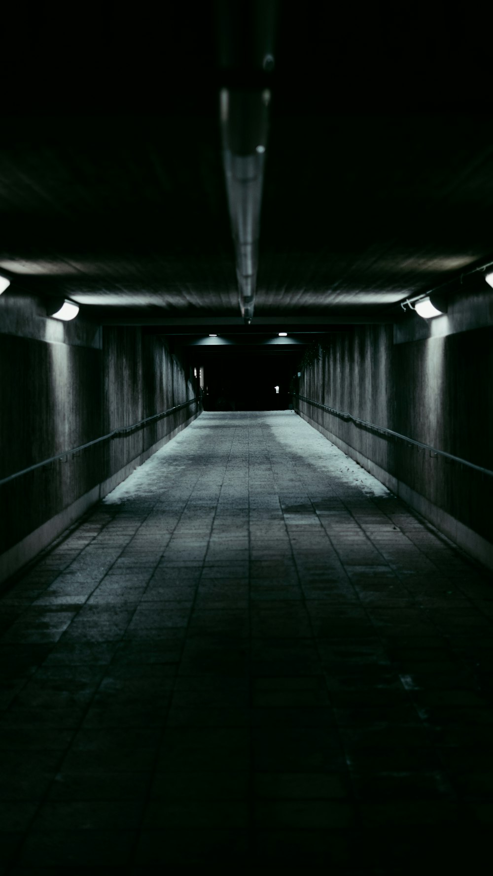 a dark tunnel with a long walkway between two walls