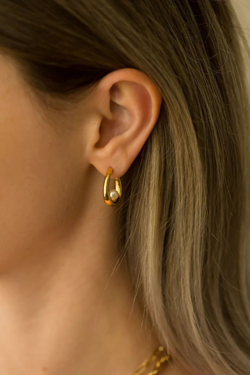 Adult woman wearing a sculptural gold hoop earring