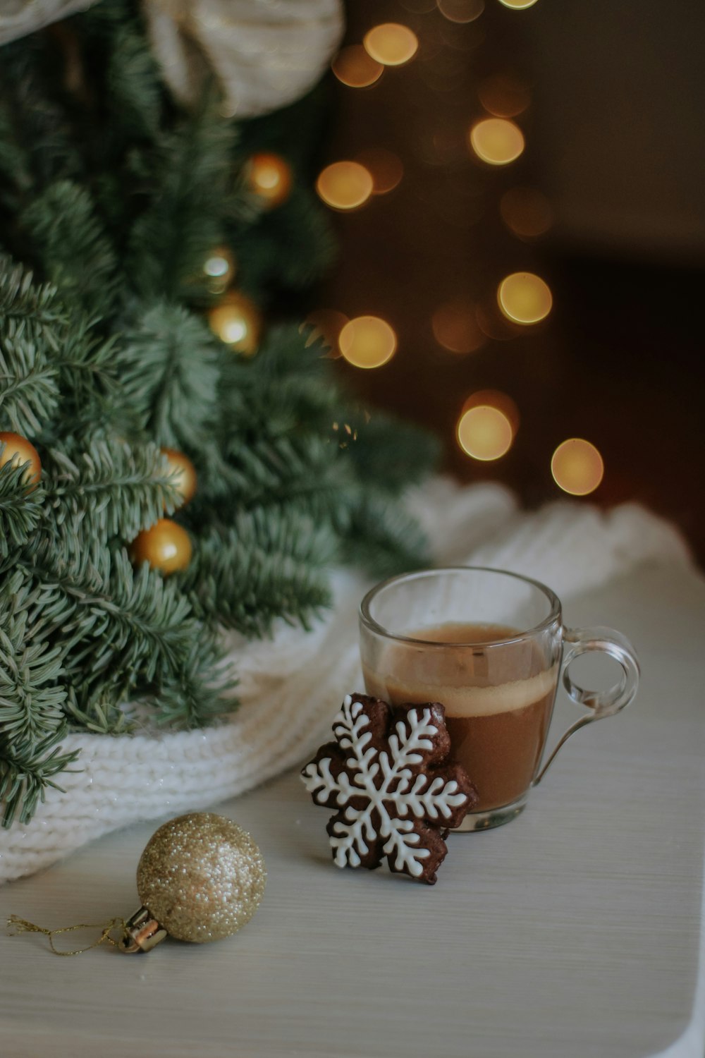 a cup of hot chocolate next to a christmas tree