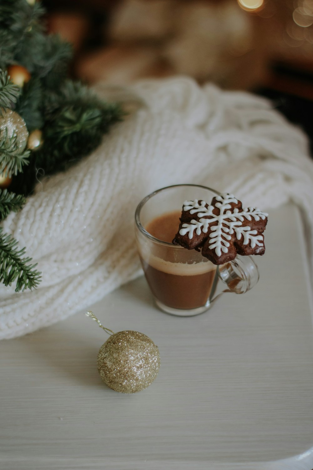 Una taza de chocolate caliente junto a un árbol de Navidad