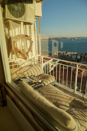 Sunlit balcony overlooking a peaceful neighborhood with comfortable seating.