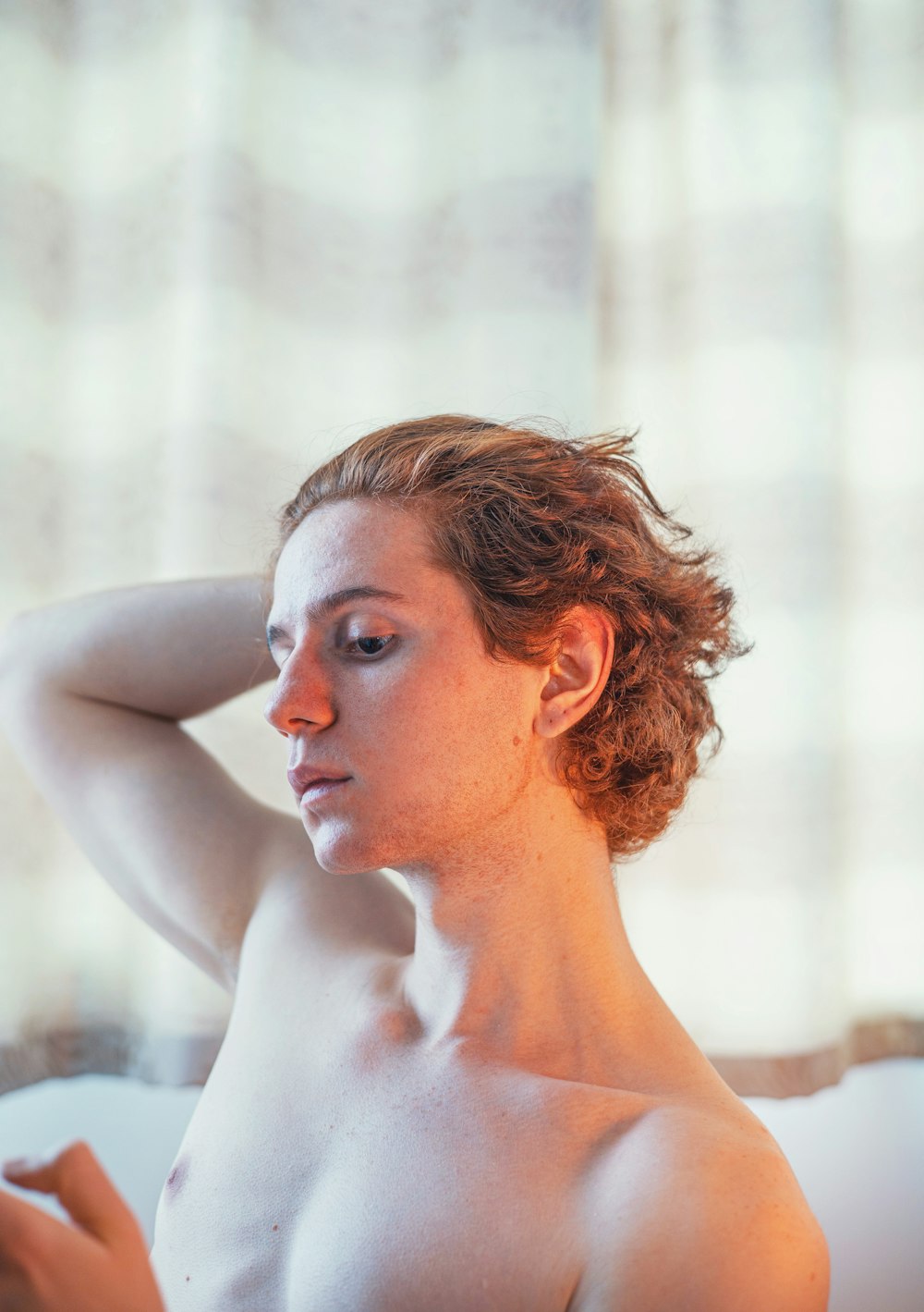 a naked woman sitting on a bed with her hand on her head