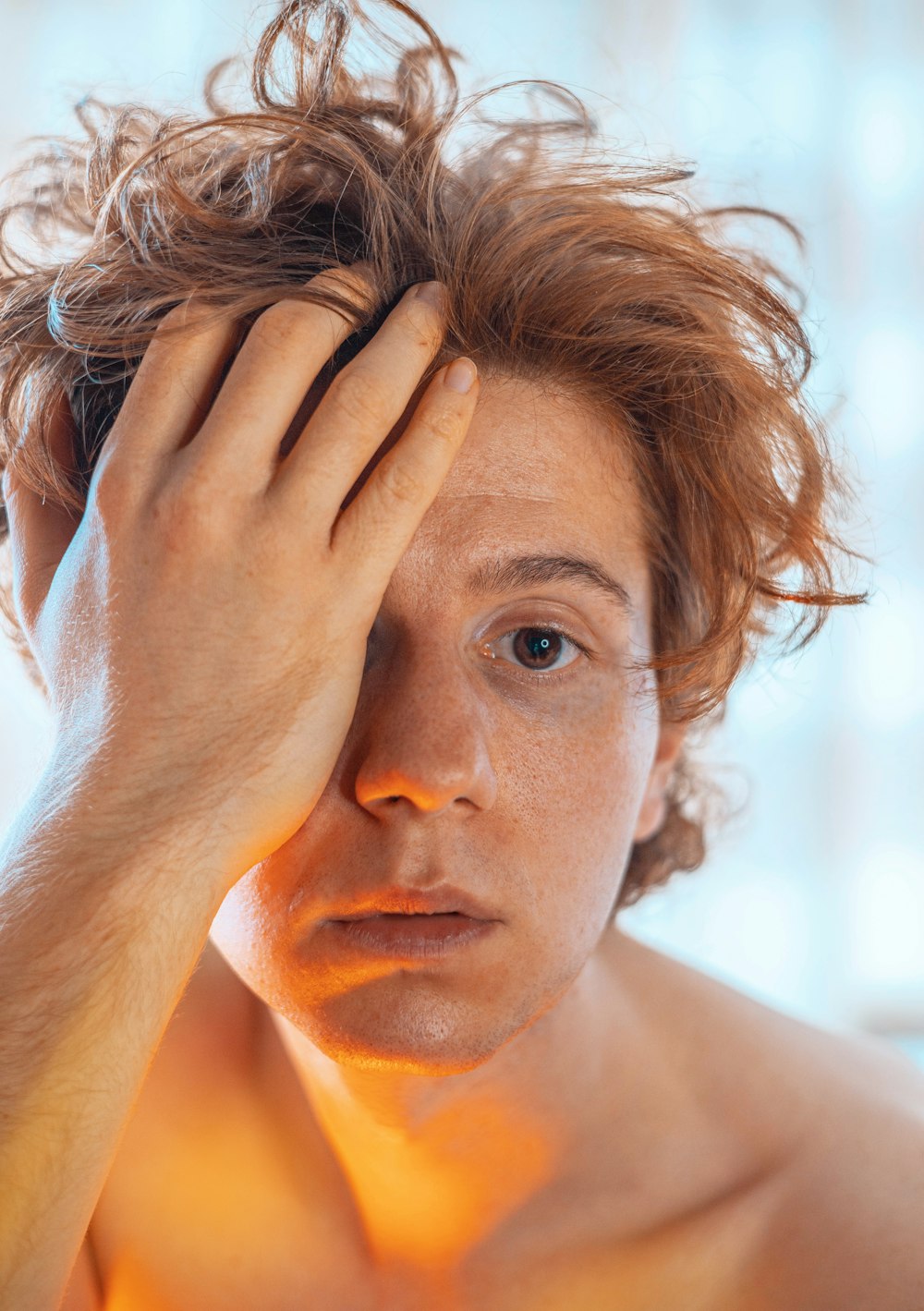 a shirtless man holding his head with his hands