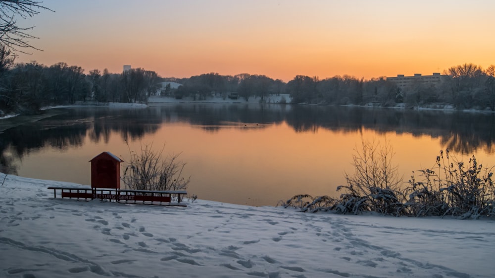 a bench sitting next to a lake covered in snow