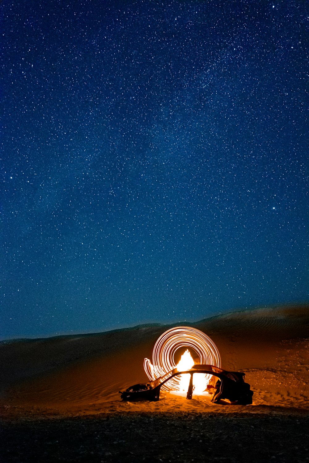 a person sitting in front of a campfire under a night sky filled with stars