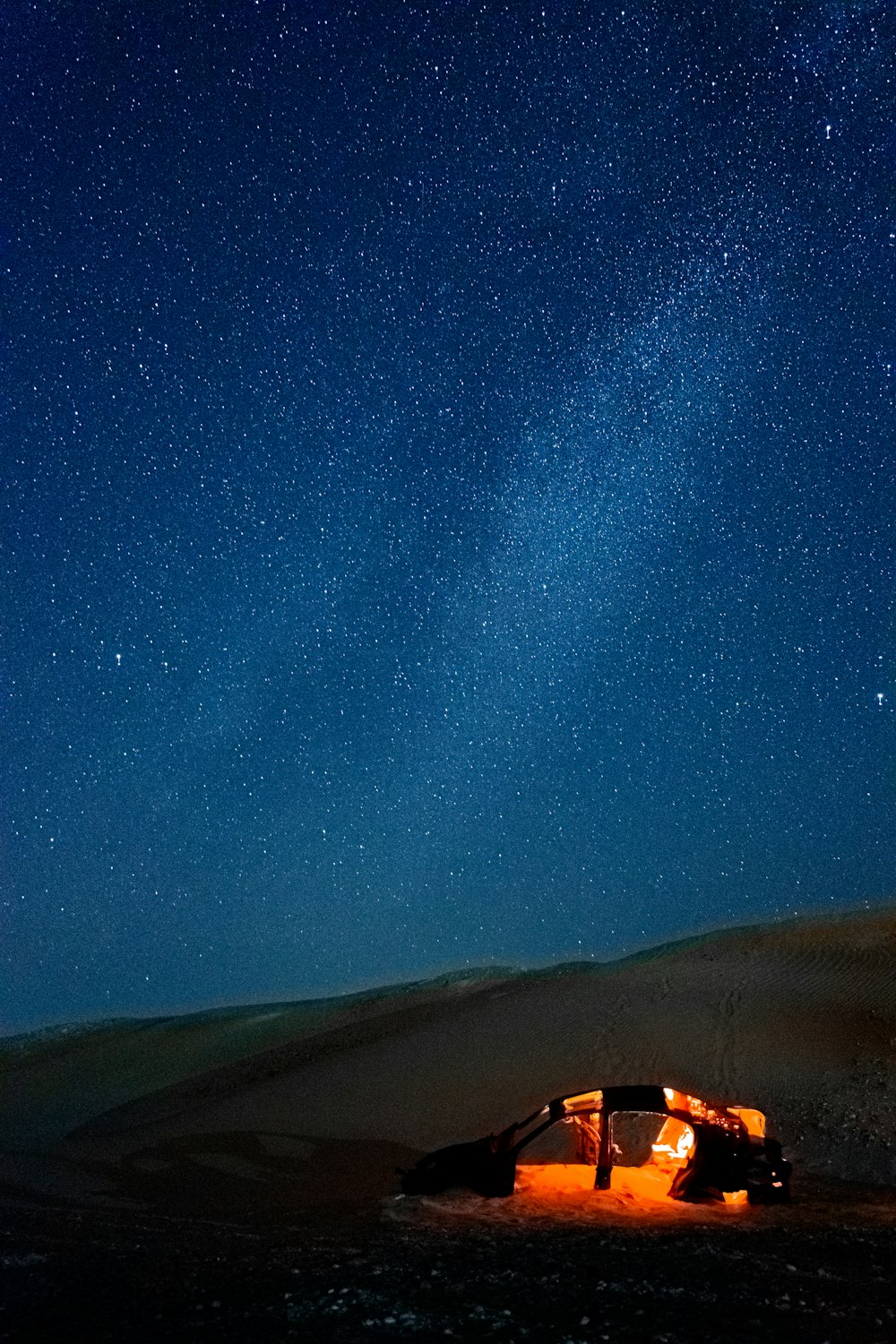 a tent in the middle of a desert under a night sky filled with stars