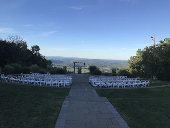 A serene outdoor ceremony setting with white chairs and soft sunlight.