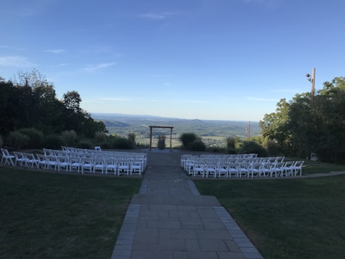 A panoramic view of a grand outdoor wedding venue set against a sunset sky, filled with happy guests.