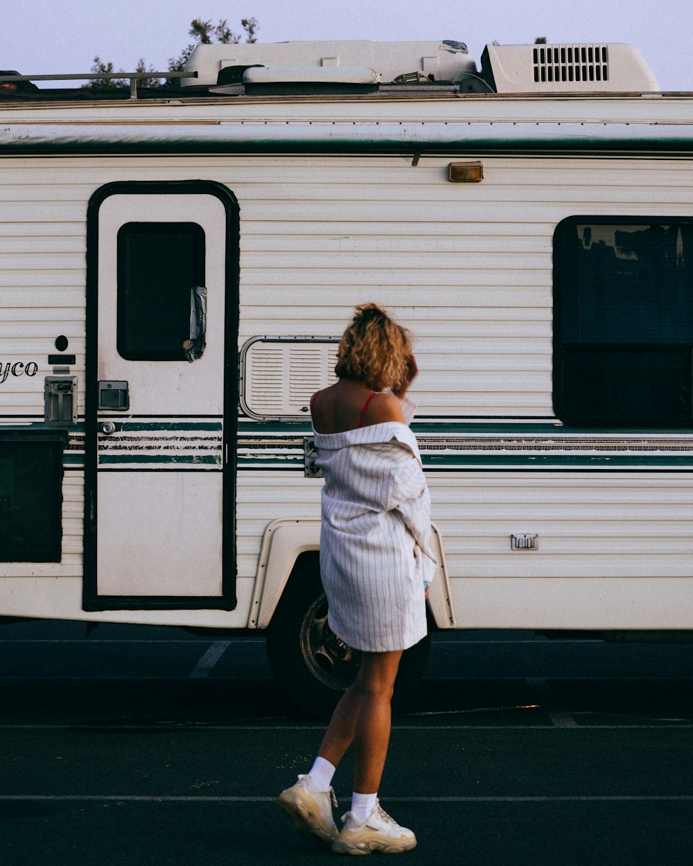 a woman in a white dress standing in front of a trailer