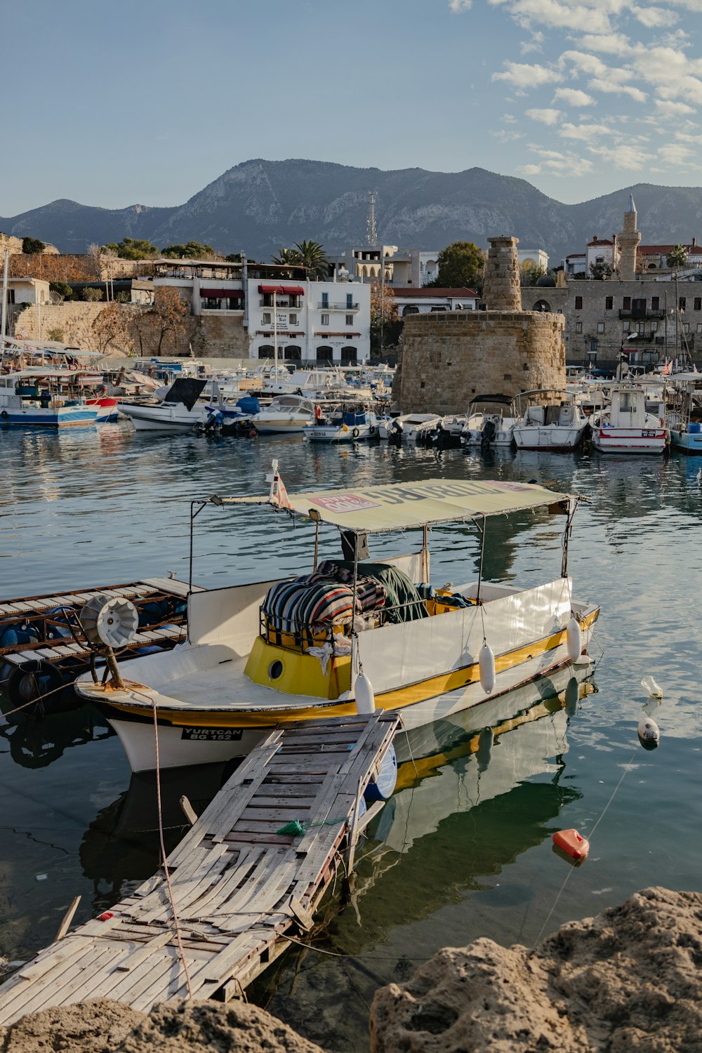 a yellow and white boat docked in a harbor