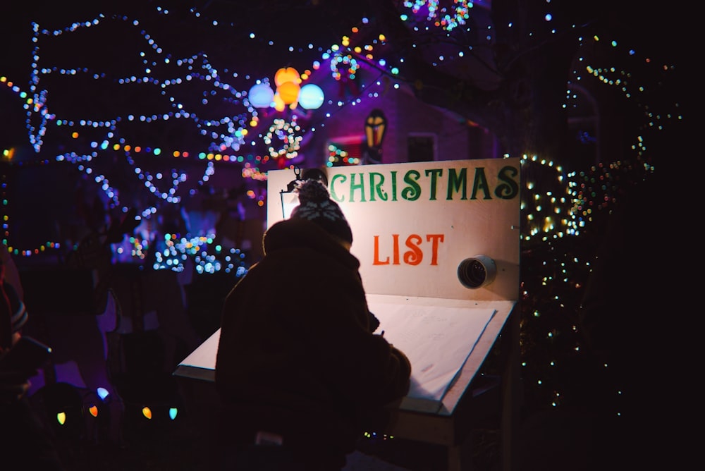 a person sitting on a bench in front of a christmas light display