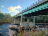 A sturdy concrete bridge spanning a river, with workers finishing the final touches.