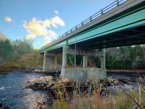 A sturdy concrete bridge spanning a river, with workers finishing the final touches.