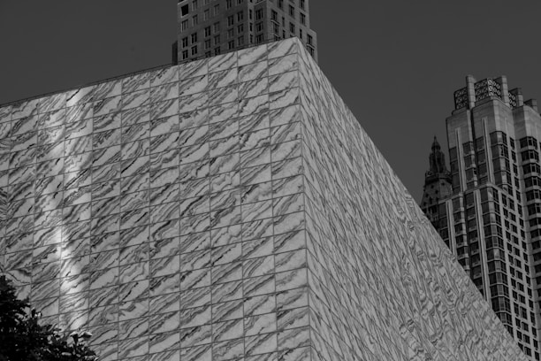 A modern office building with construction workers and marble slabs in the foreground.