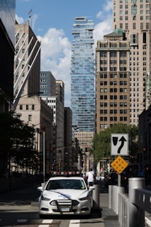 a white car driving down a street next to tall buildings