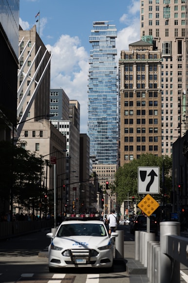 a white car driving down a street next to tall buildings
