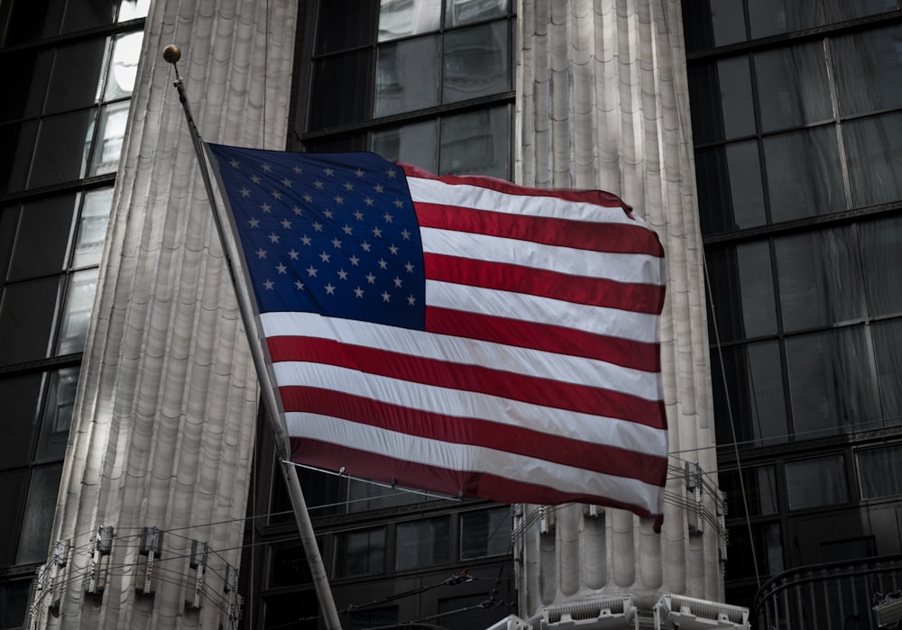 a large american flag flying in front of a building