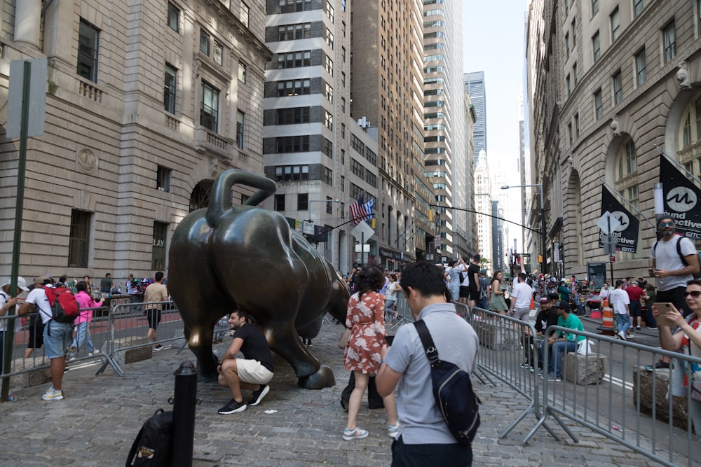 a crowd of people standing around a statue of a bull