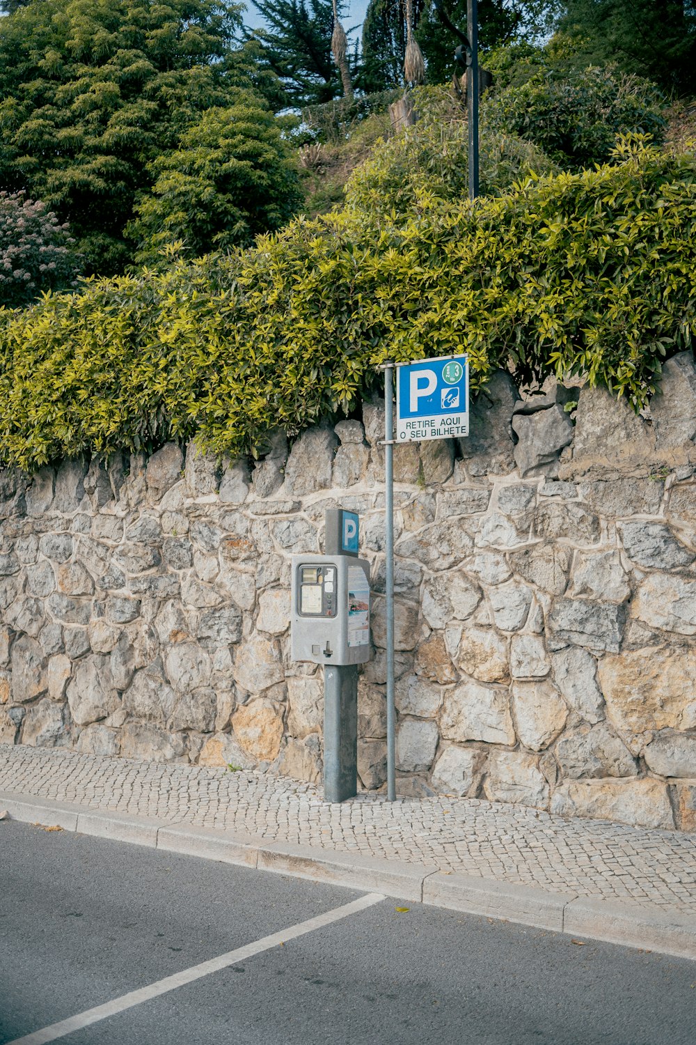 a parking meter next to a stone wall