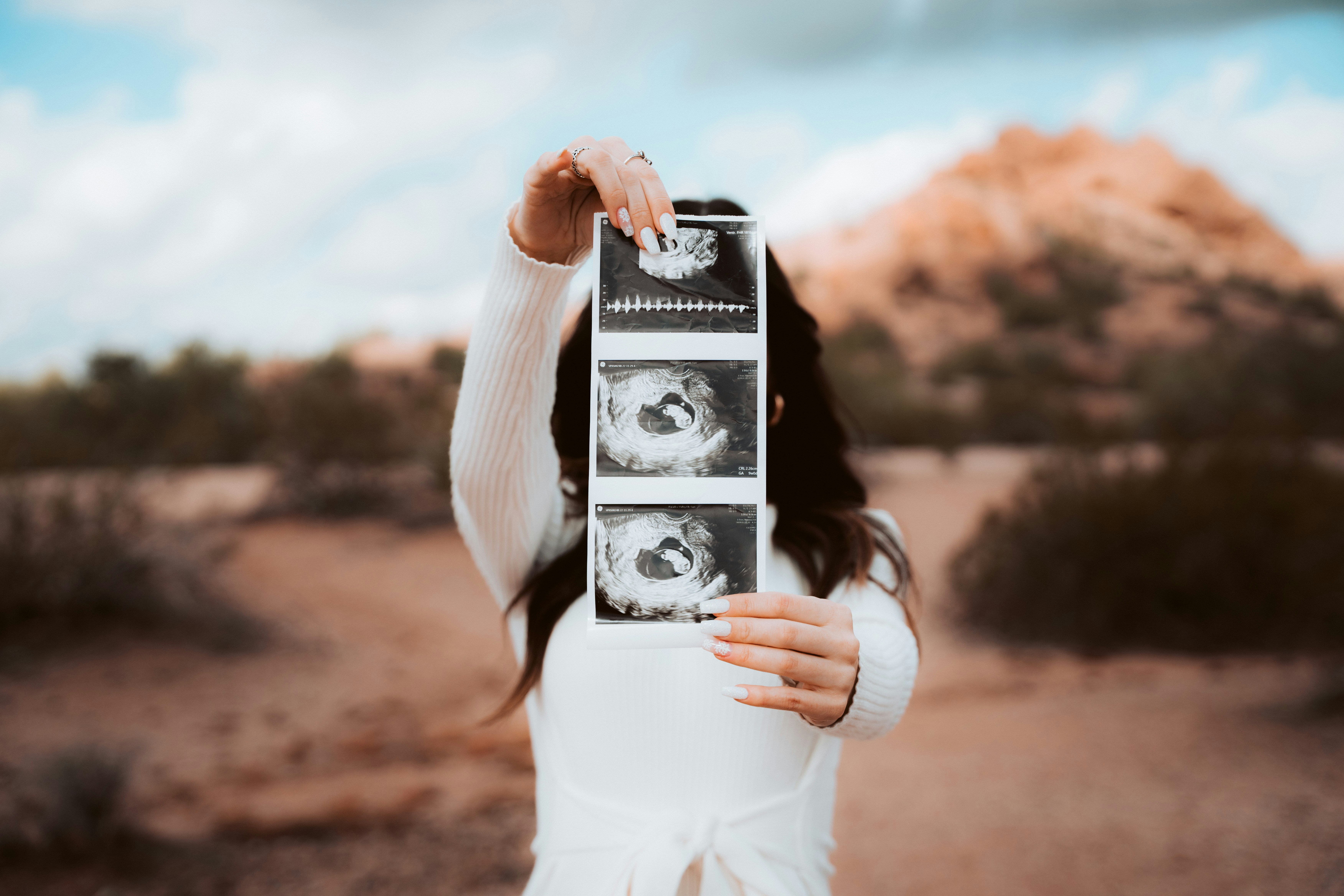 a woman holding up a picture of a baby in the desert