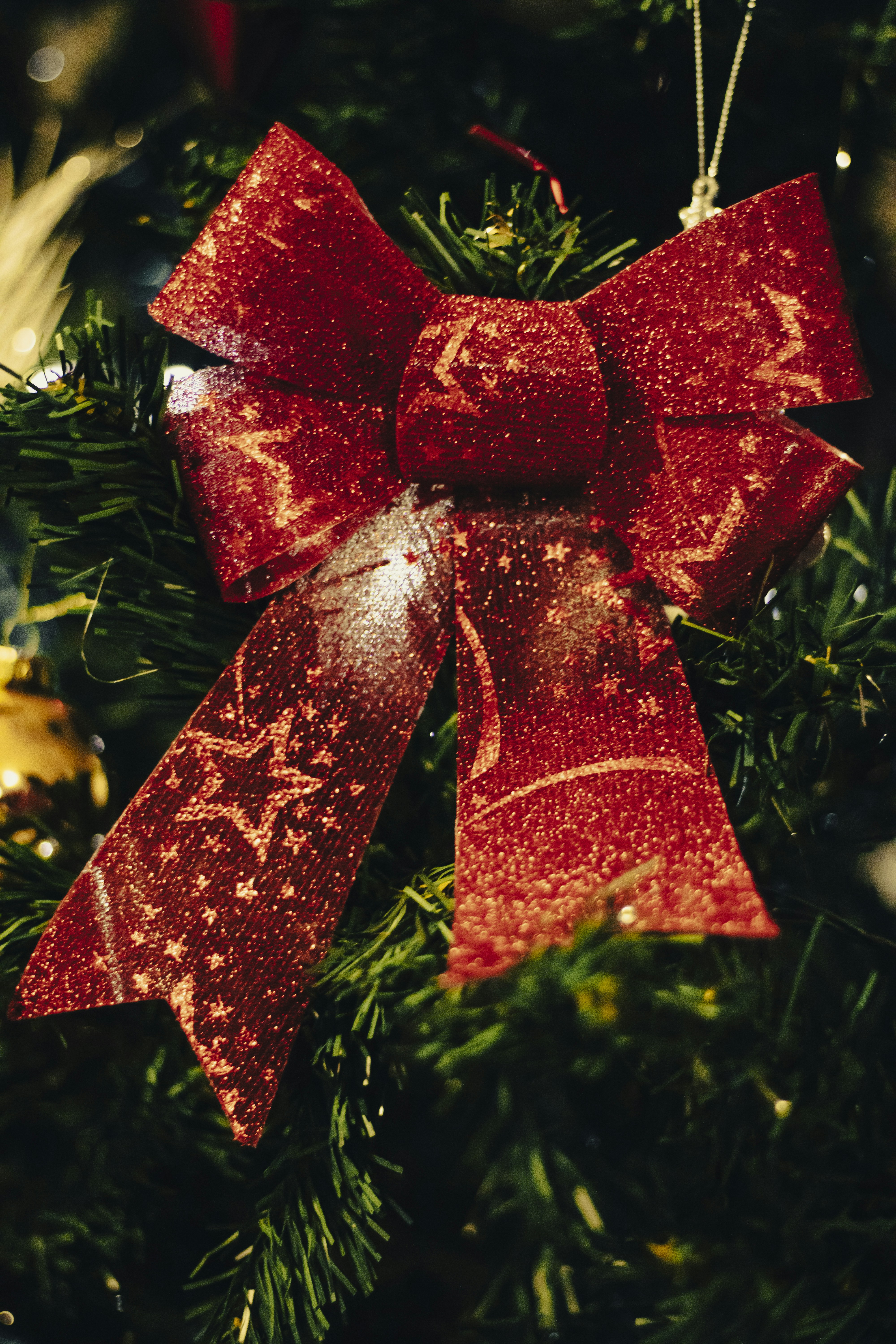a red bow hanging from a christmas tree