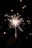 A bright sparkler is being held in a dark setting, with sparks radiating outward and creating a playful, lively atmosphere. The background features soft bokeh circles adding to the festive mood.