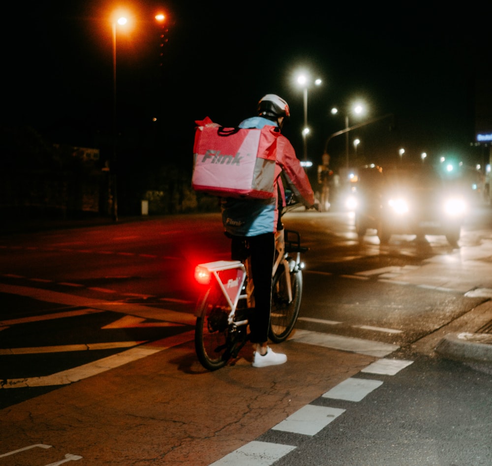 a person riding a bike on a city street at night